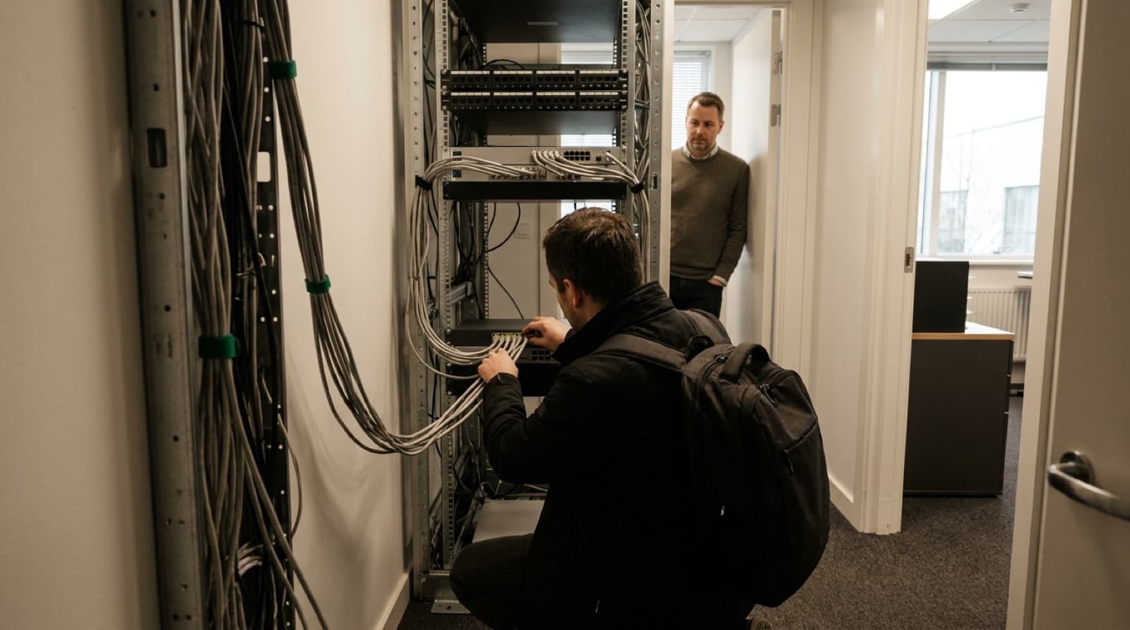 Informatyk odłącza kable sieciowe w szafie serwerowej